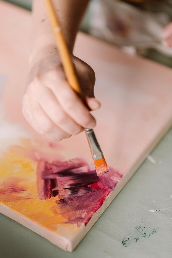 A hand painting a vibrant abstract design on canvas using a brush. Perfect for art and creativity themes.