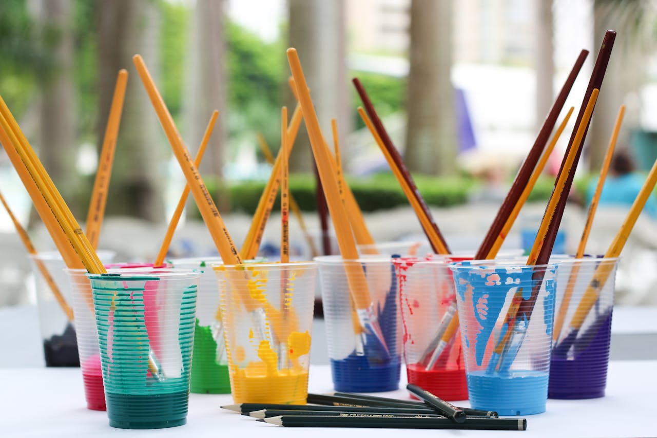 our-services-1 Vibrant paint brushes and pencils in plastic cups for arts and crafts.