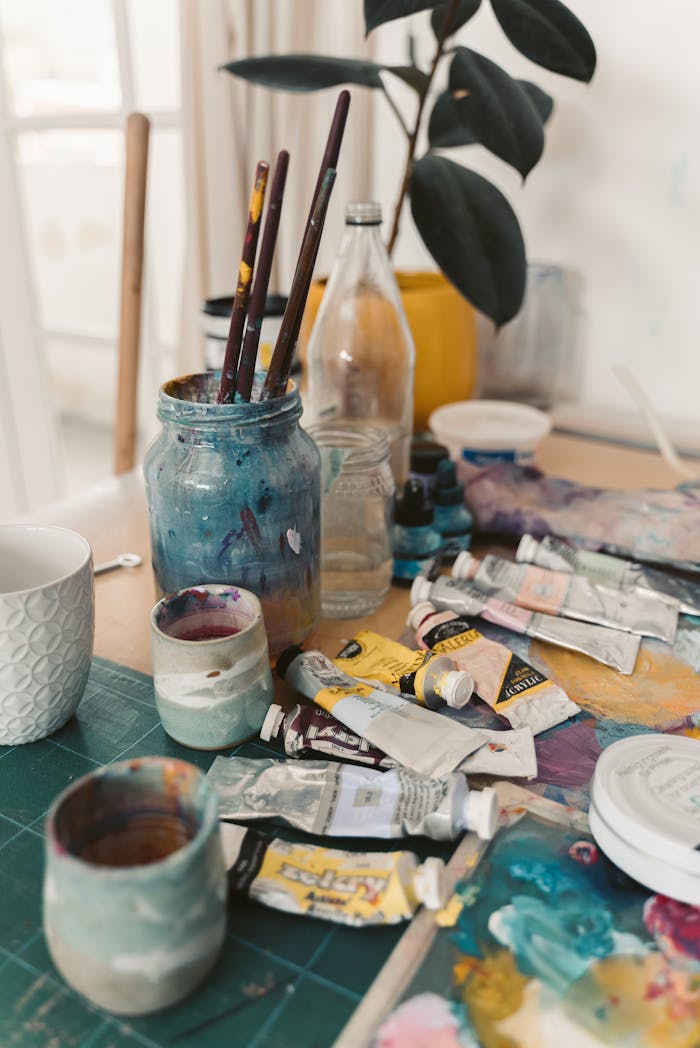 our-services-2 A vibrant display of art supplies including oil paints and brushes on a wooden table in a creative studio.